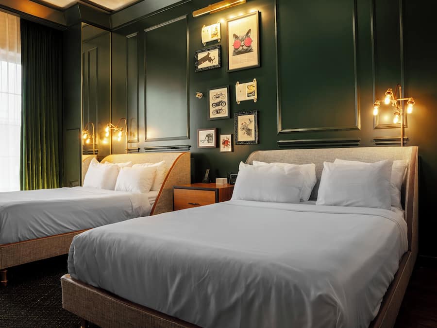 A hotel room with two beds, a nightstand, and wall-mounted artwork.
