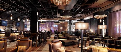 A modern bar area with leather seating, chandeliers, and a bar counter.