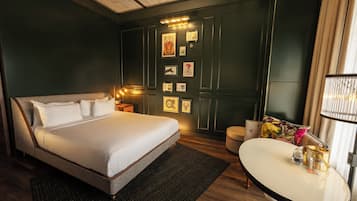 Una habitación de hotel con una cama grande, una mesa redonda pequeña y una pared decorada con cuadros.