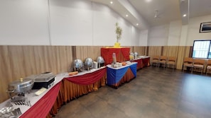 A banquet hall with tables set for a meal, a stage with a backdrop, and a seating area with chairs. - Pai Vista, KR Road, Bangalore (Bengaluru)