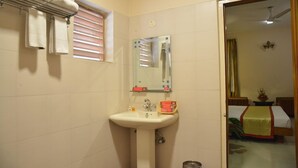 Un baño con lavamanos, espejo, toallero y ventana con persianas.