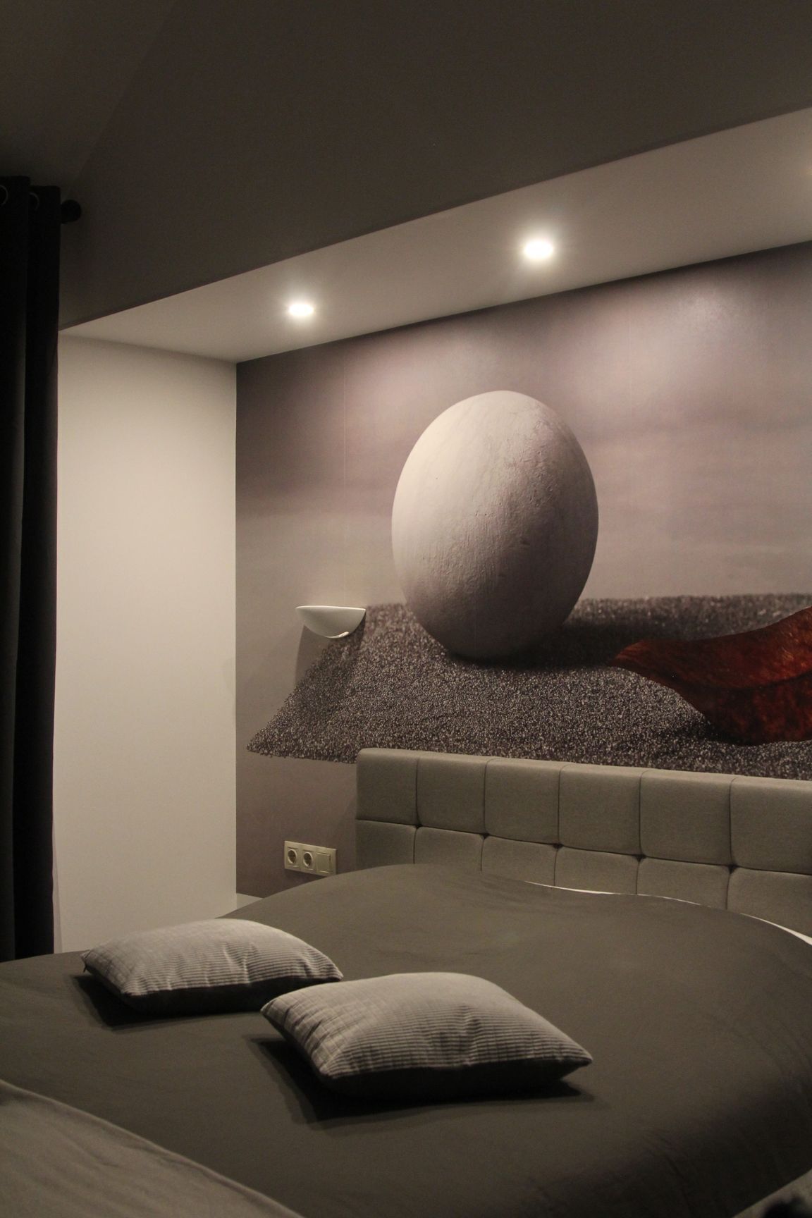 Une chambre moderne avec un grand lit, une tête de lit et un objet sphérique fixé au mur.