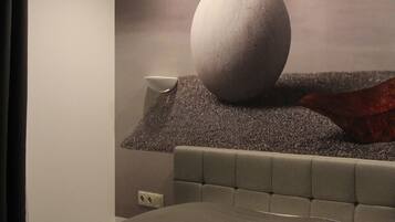 Une chambre moderne avec un grand lit, une tête de lit et un objet sphérique fixé au mur.