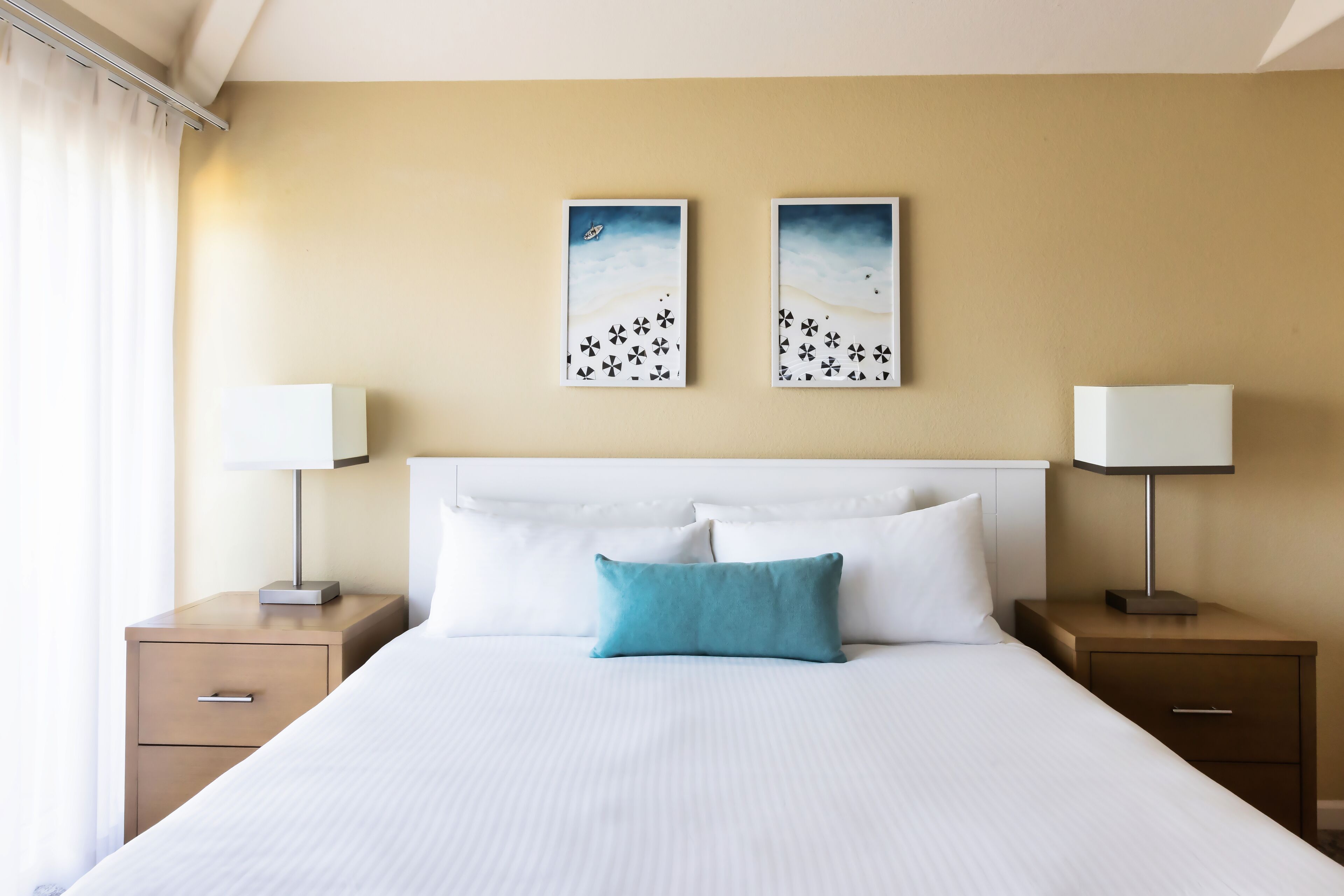 Una camera d'albergo con un letto grande, due comodini, una testiera e due quadri appesi al muro.