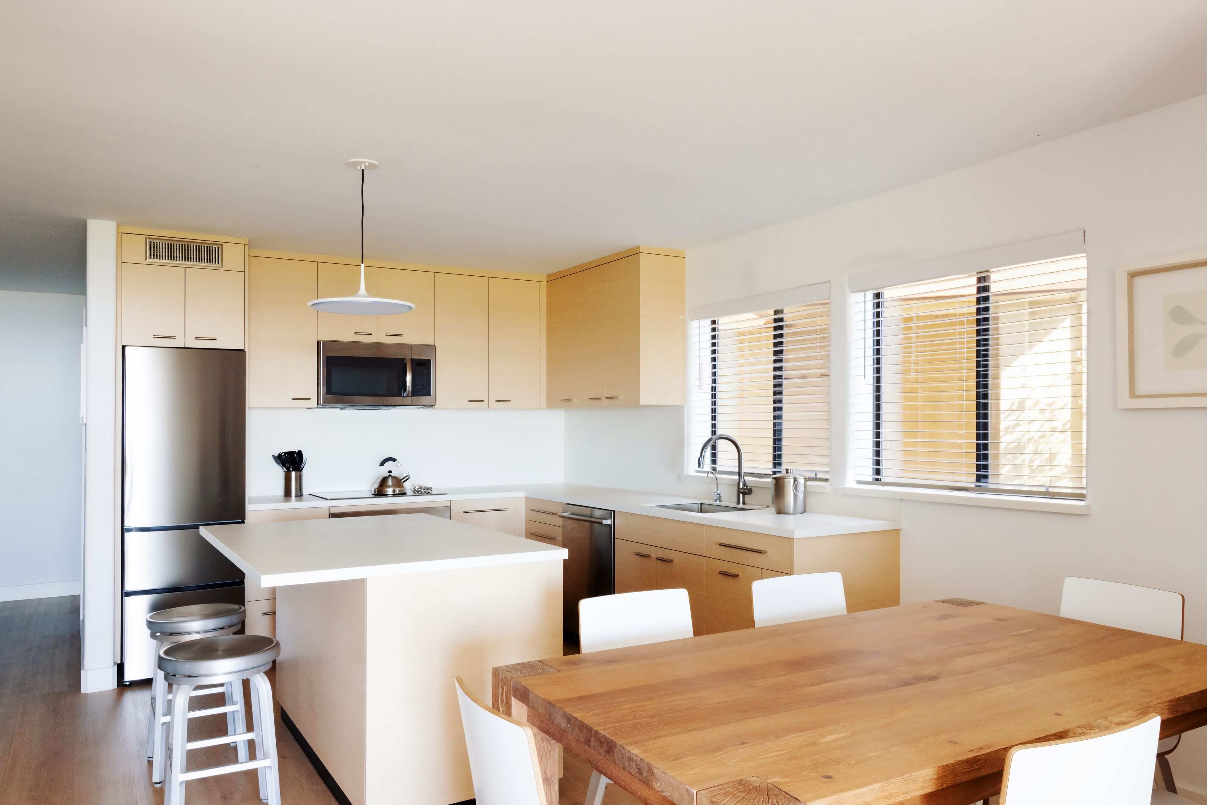 Una cocina moderna con una isla central, electrodomésticos de acero inoxidable y armarios blancos.