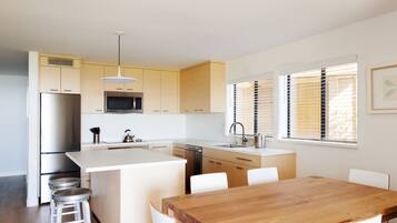 Una cocina moderna con una isla central, electrodomésticos de acero inoxidable y armarios blancos.