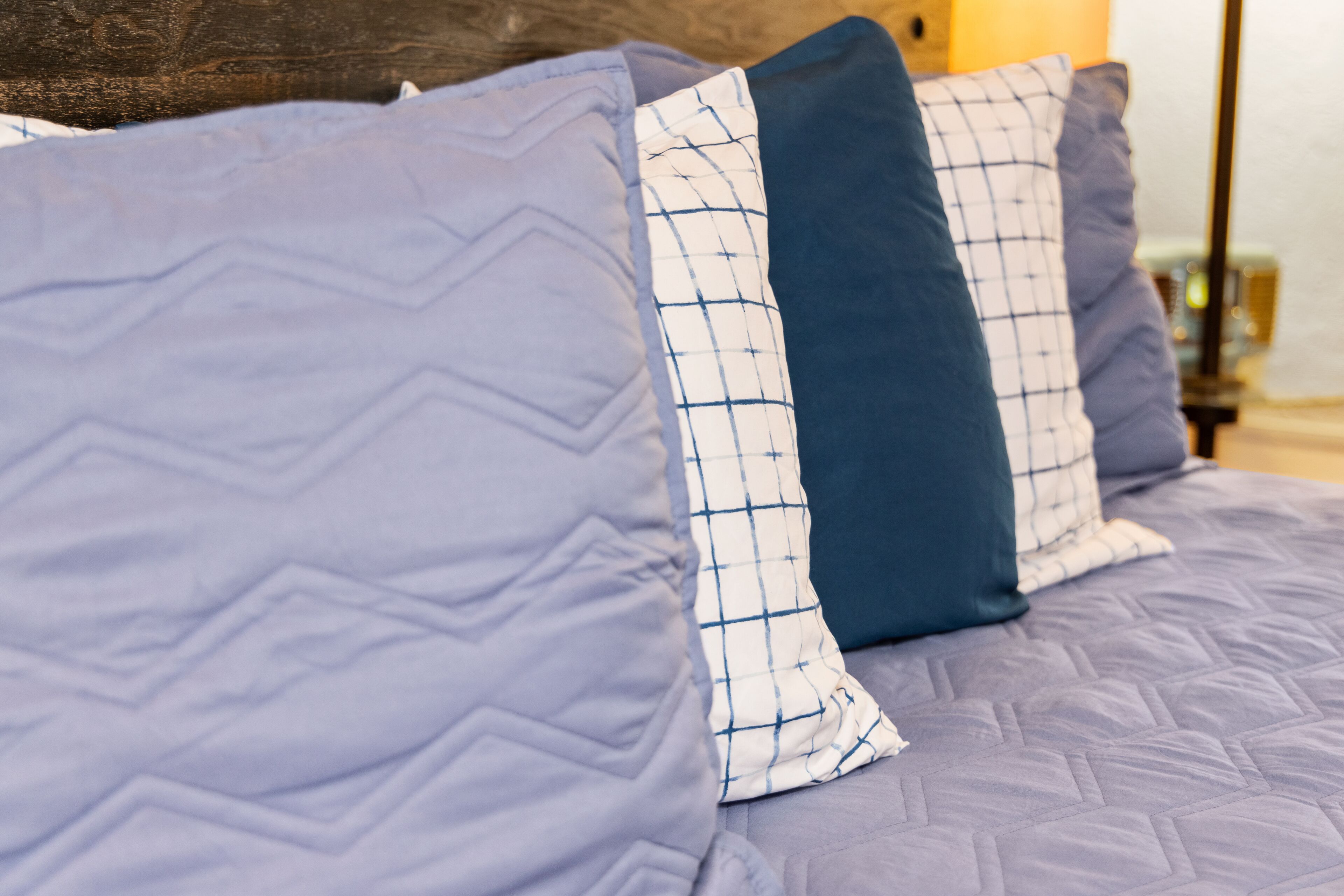 A bed with a quilted headboard and pillows with a checkered pattern.