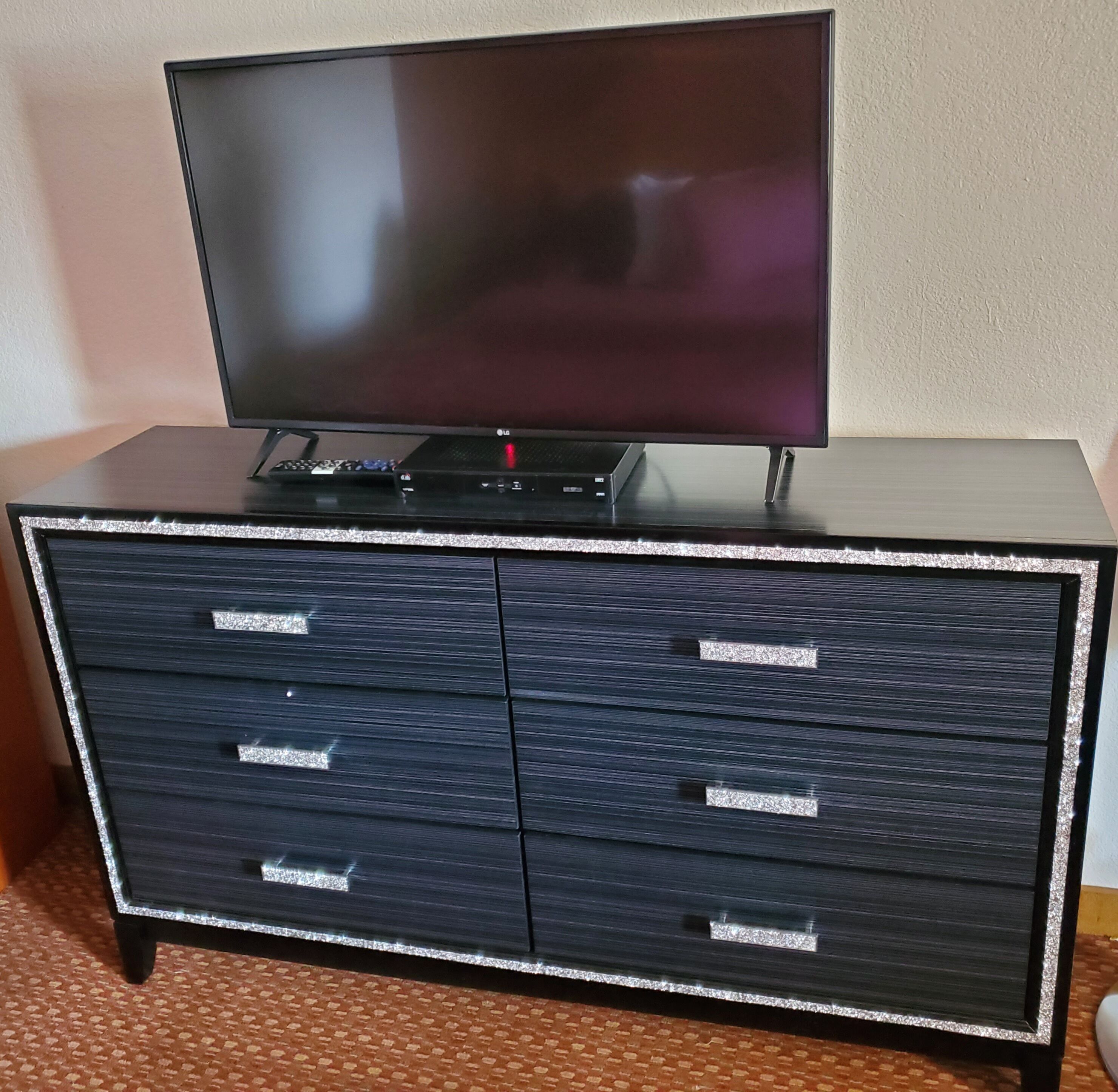 A flat-screen TV on a black entertainment unit with four drawers.