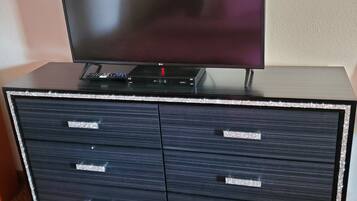 A flat-screen TV on a black entertainment unit with four drawers.