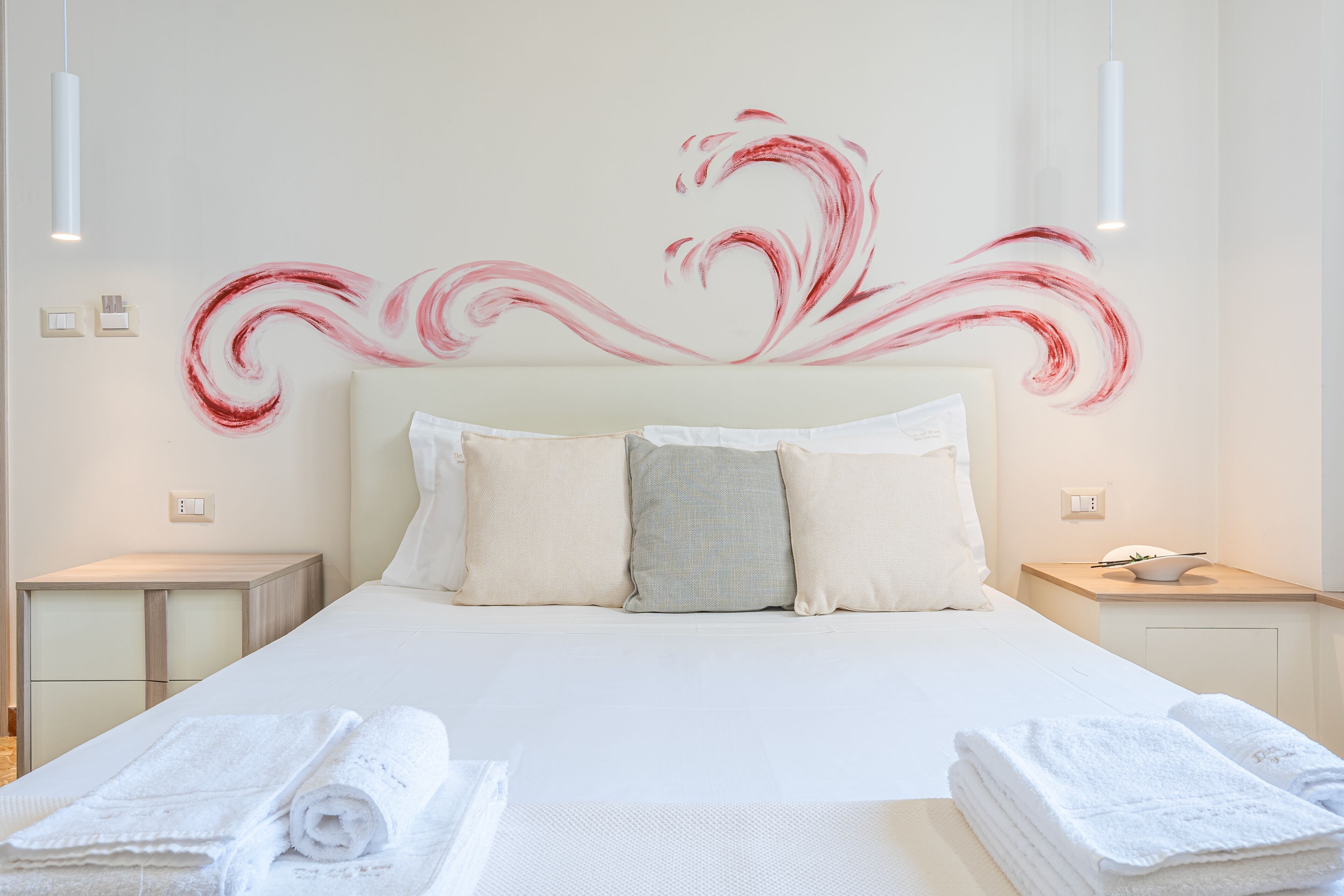 A neatly made bed with white linens, a headboard, and decorative wall art.