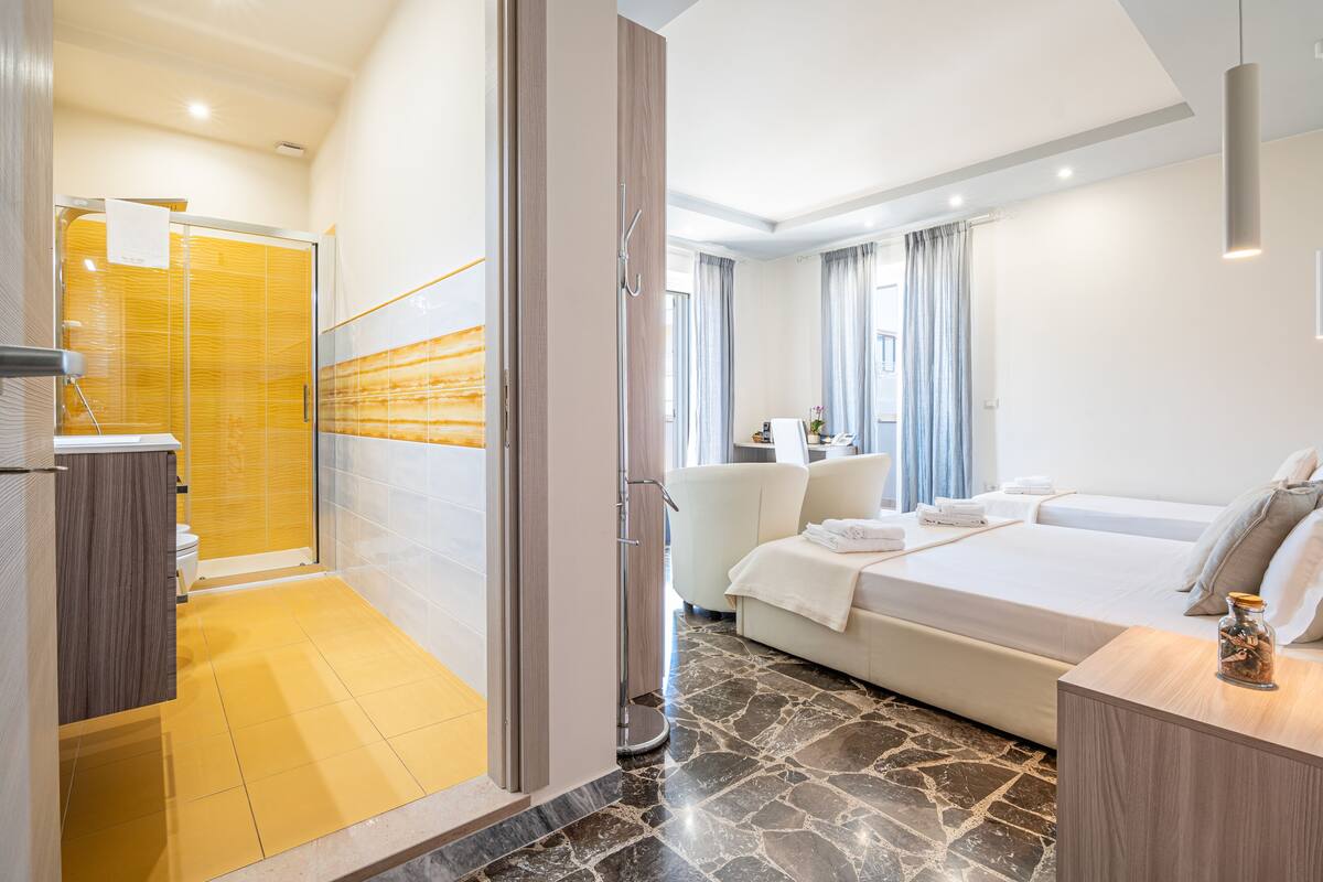 Una habitación de hotel moderna con ducha, cama, zona de estar y vistas a la ciudad.
