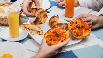 A breakfast setting with croissants, a glass of orange juice, and a plate of food.