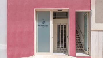 Entrada de un edificio con puerta de vidrio, una escalera y un letrero que dice 'DEI DEL MARE'.