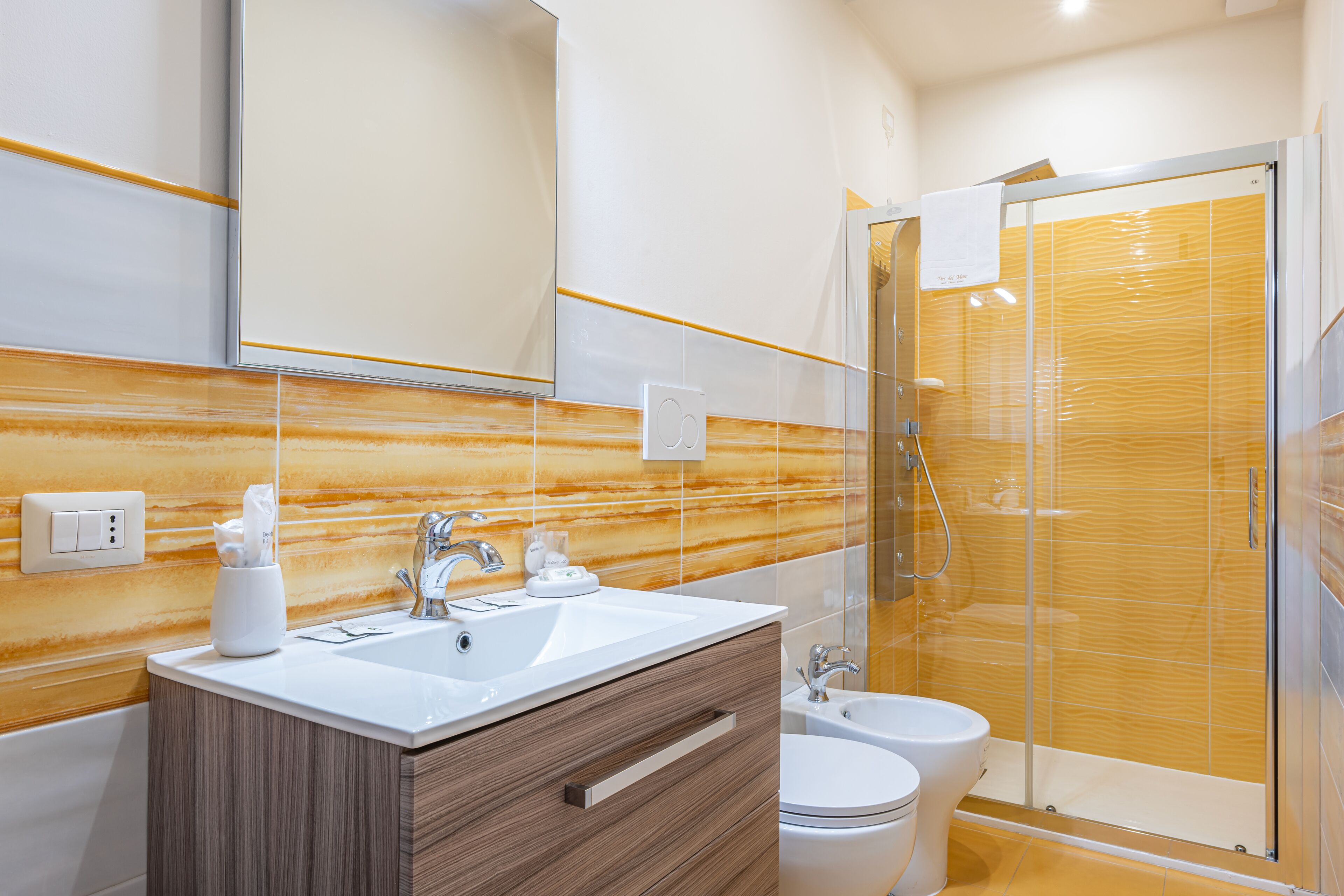 Une salle de bain moderne équipée d’un meuble-lavabo, d’un évier, d’un miroir et d’une douche à l’italienne.