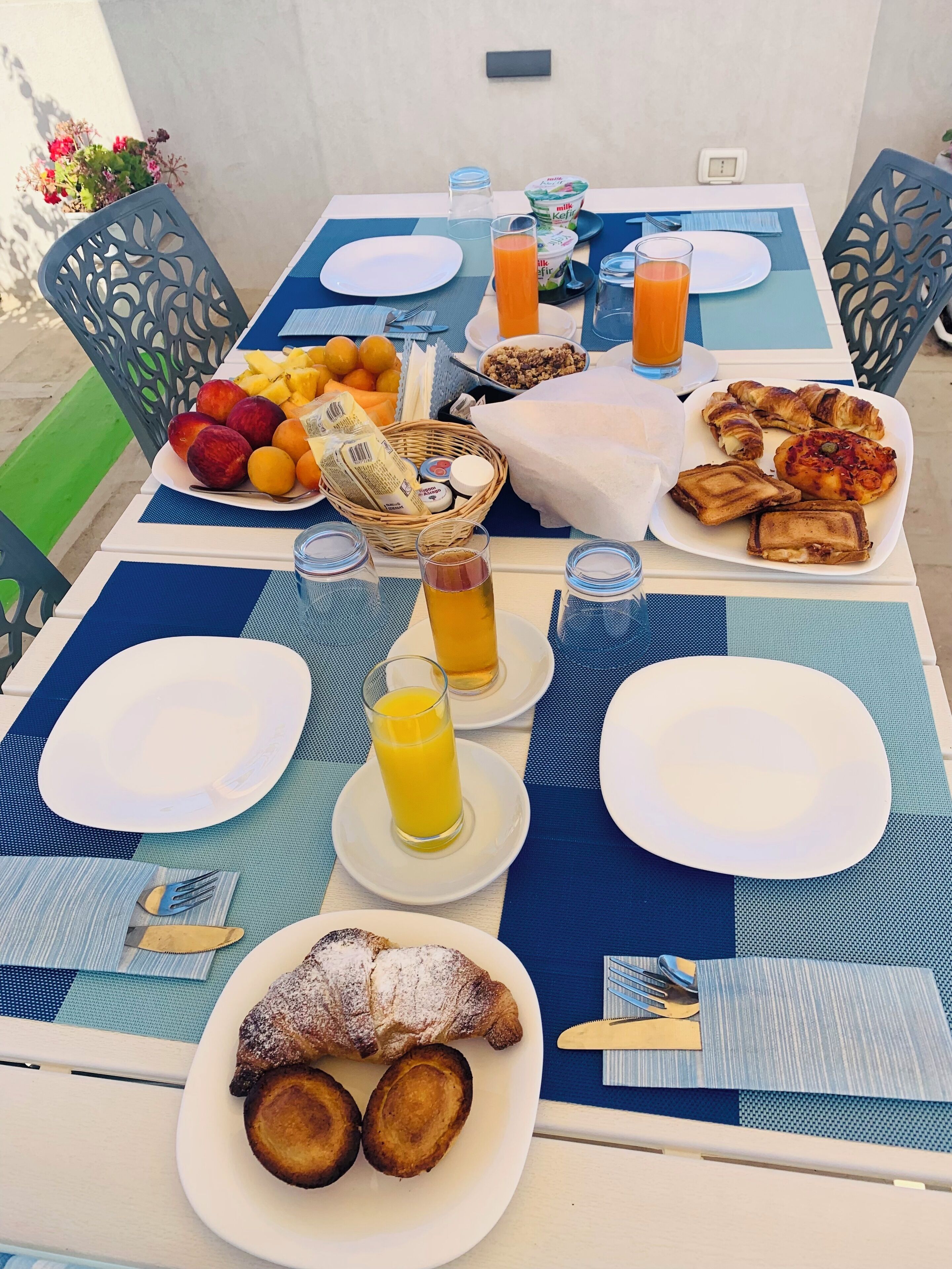 Ein Frühstückstisch mit Tellern, Gläsern und einem Obstkorb.