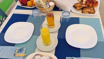 Ein Frühstückstisch mit Tellern, Gläsern und einem Obstkorb.