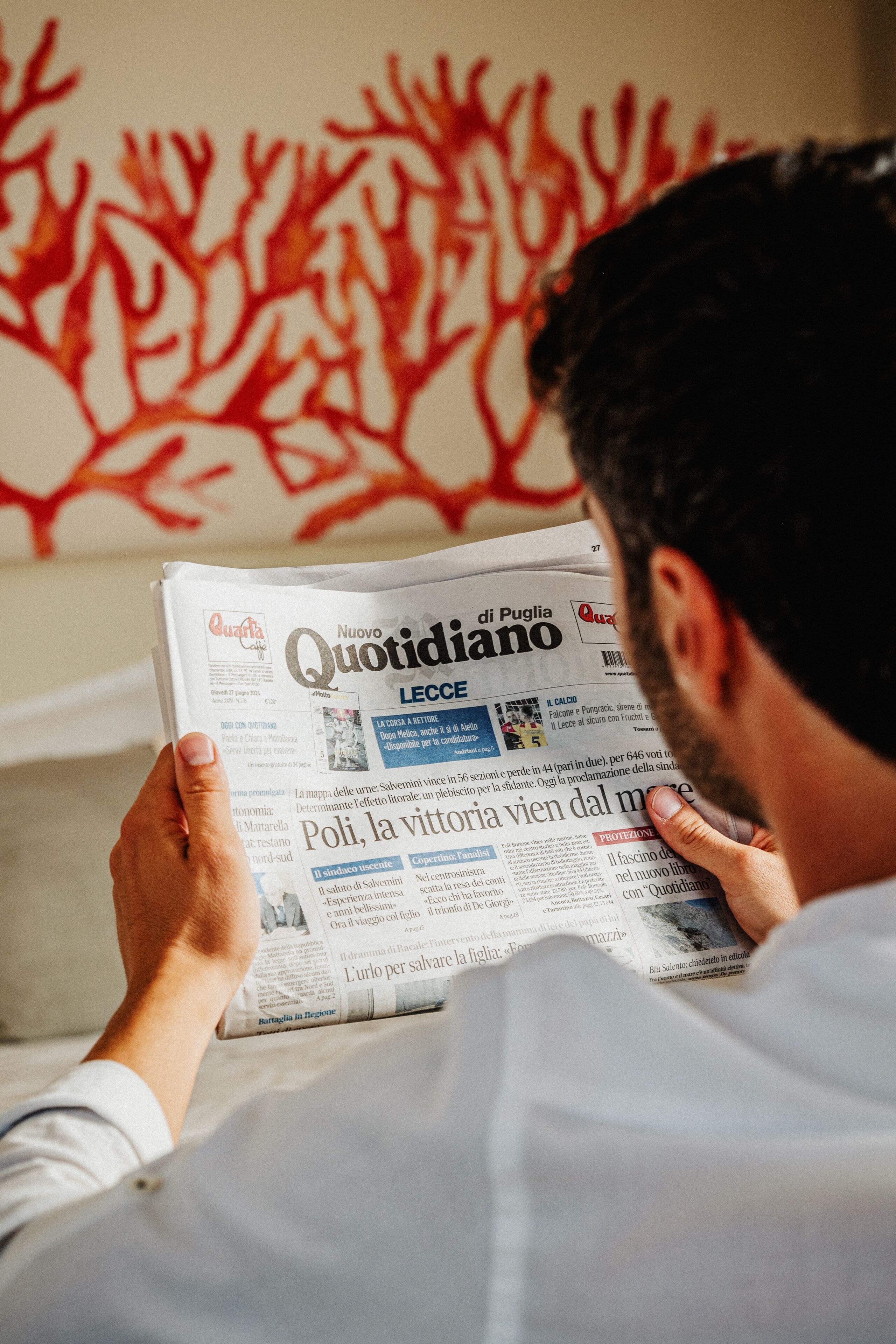 A person reading a newspaper with the headline 'Nuovo Quotidiano.'