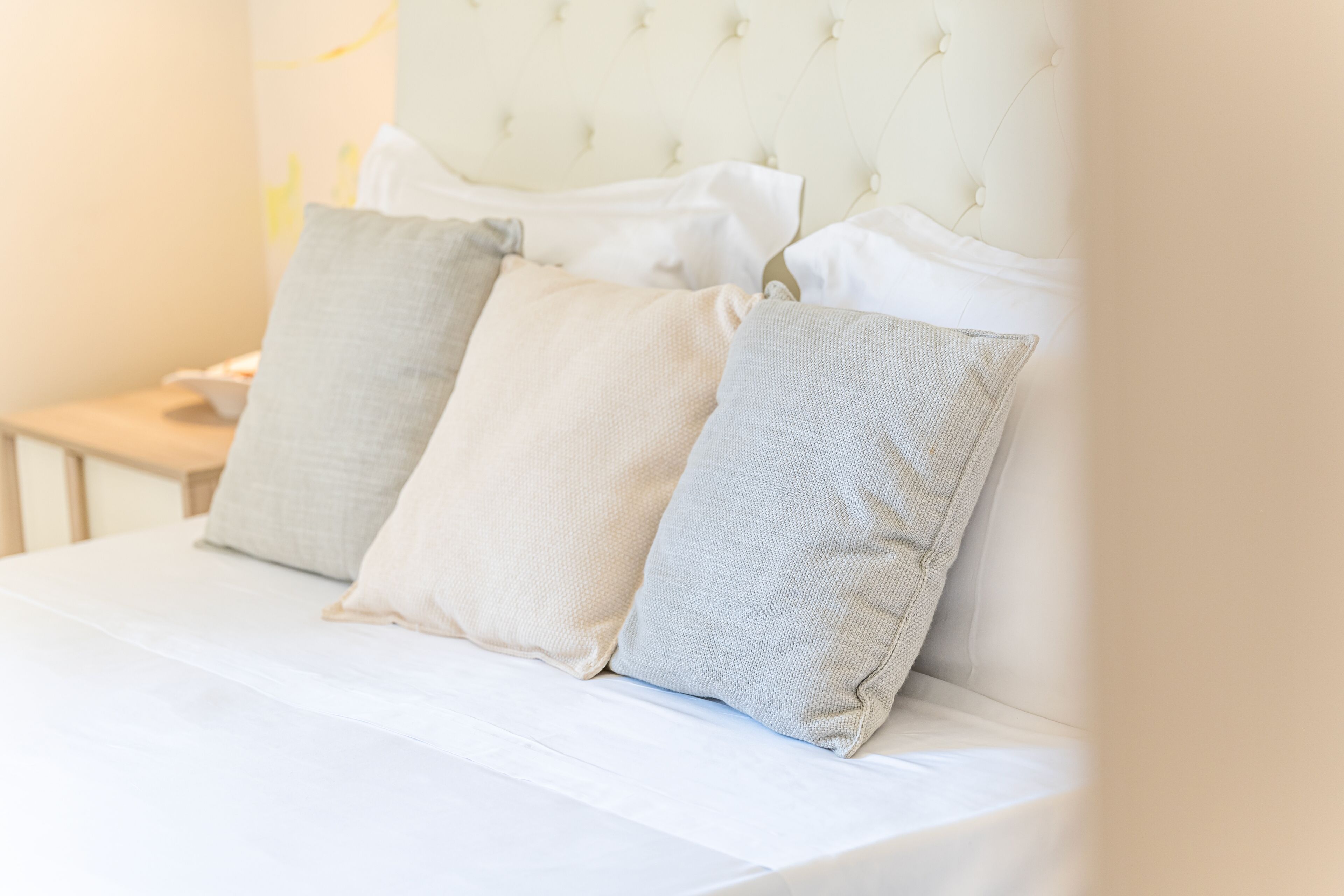 Ein Bett mit einem gesteppten Kopfteil und drei Kissen.