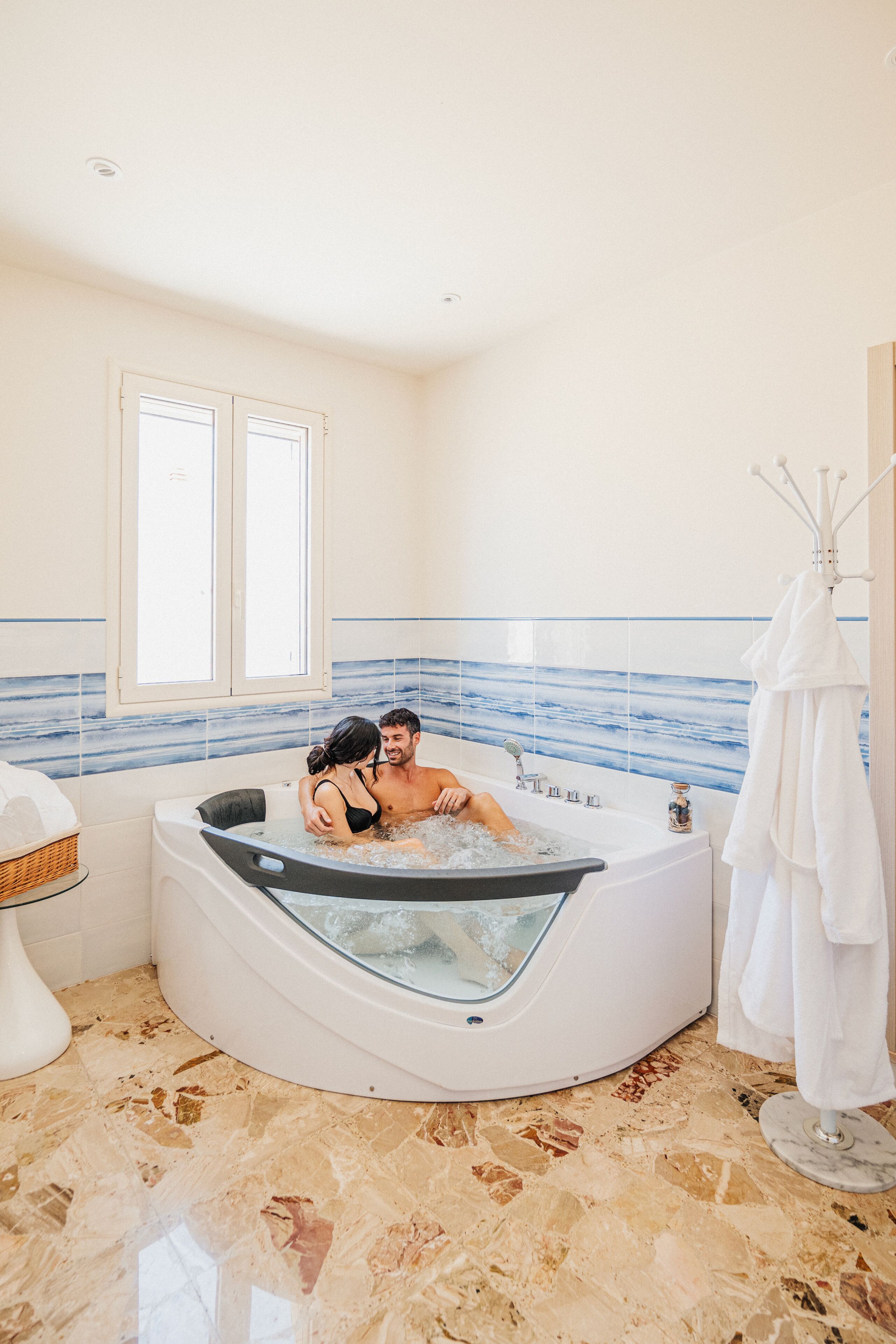 A modern bathroom with a freestanding bathtub, a window, and a towel rack.