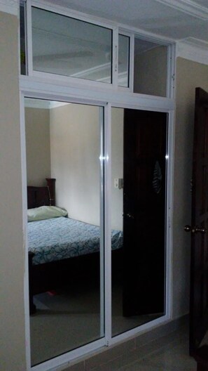 Ein Zimmer mit einem Bett, einem Kleiderschrank und einer Schiebetür.