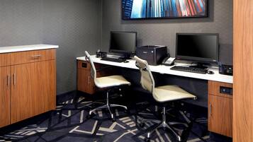 A modern office space with two desks, two chairs, and a large screen on the wall.