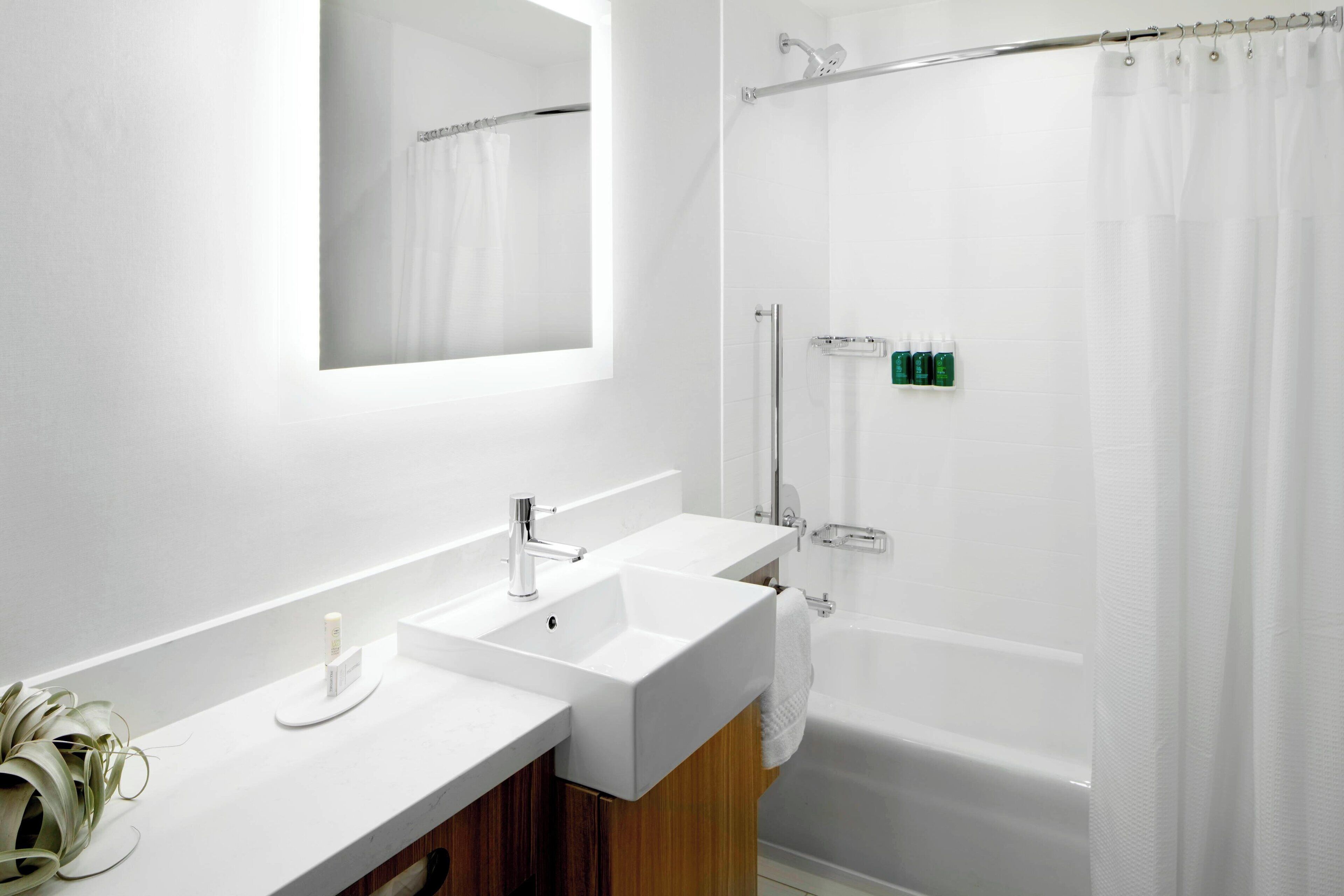 A modern bathroom with two sinks, a mirror, a shower, and a bathtub.