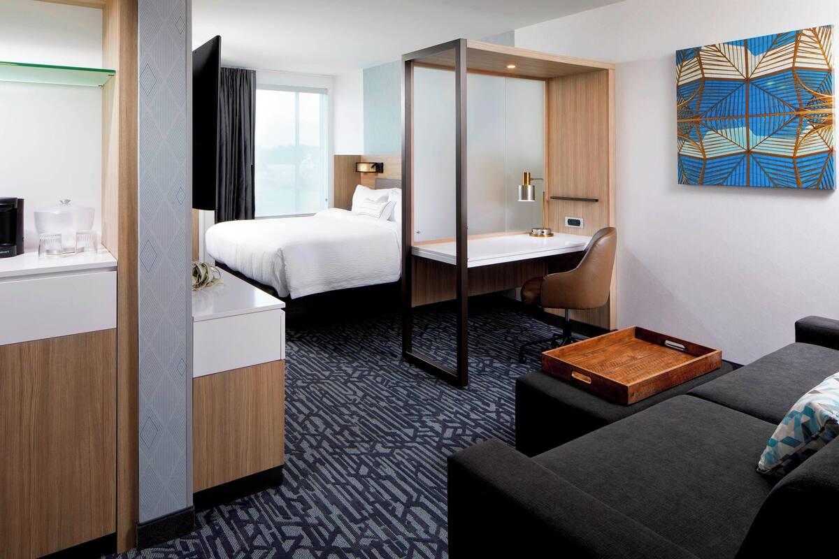 A hotel room with a bed, desk, and seating area.