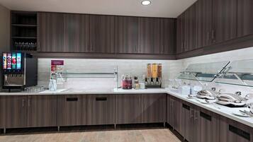 A modern kitchen with dark wood cabinets, a glass display case, and a digital menu board.