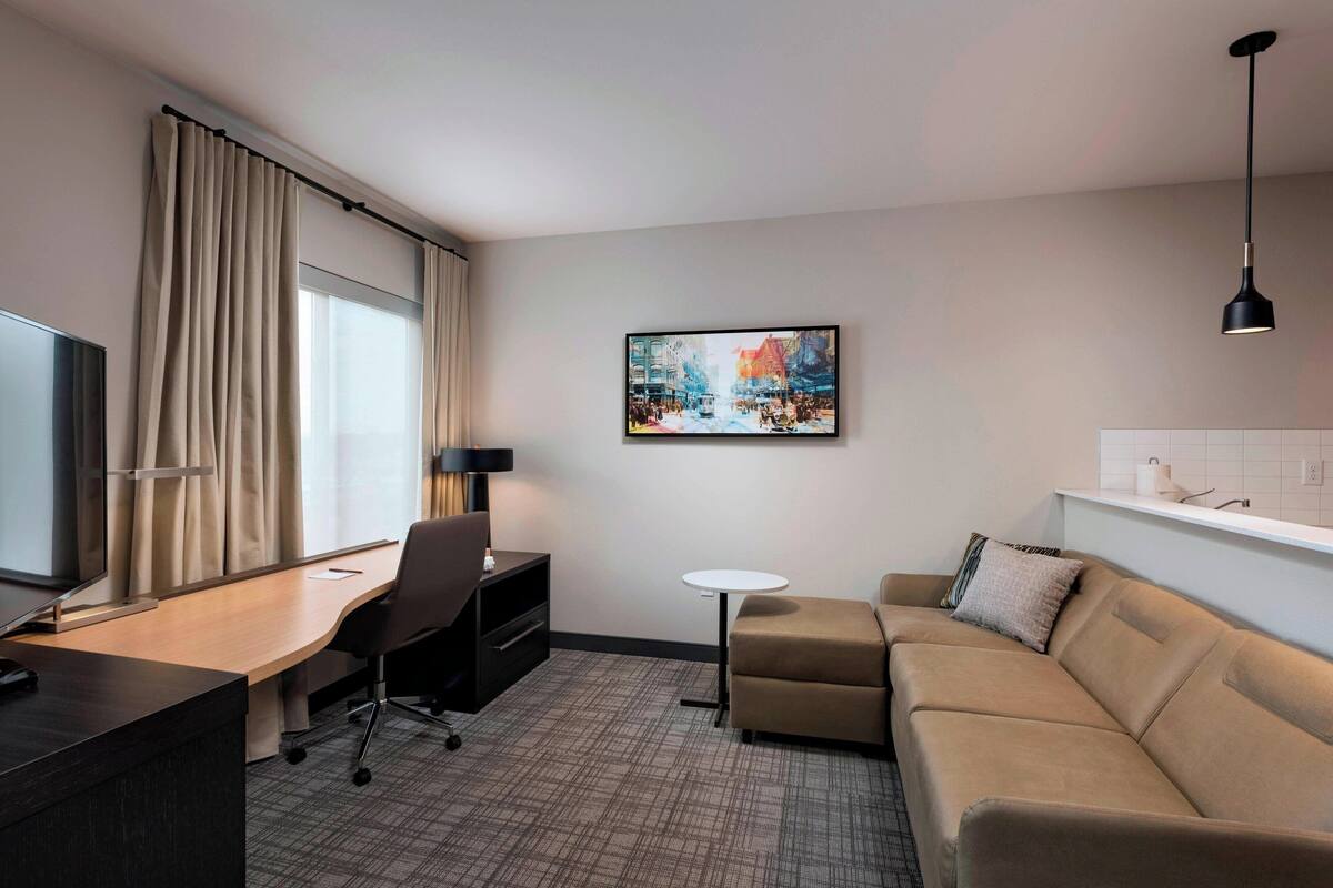 Une chambre d’hôtel équipée d’un bureau, d’une chaise, d’un canapé et d’un tableau au mur.
