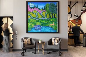 A modern lobby with a large abstract painting, two armchairs, a small table, and a reception desk.