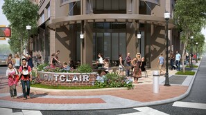 A modern building with a sign reading "MONTCLAIR" and a landscaped area with seating.
