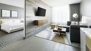 Ett modernt hotellrum med en säng, en soffa, ett soffbord och en tv som är monterad på väggen.
