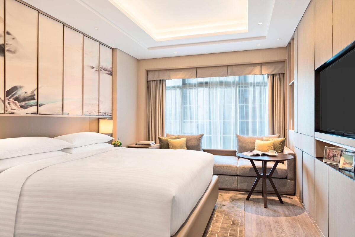 Een moderne hotelkamer met een groot bed, een bank, een klein tafeltje en een televisie.