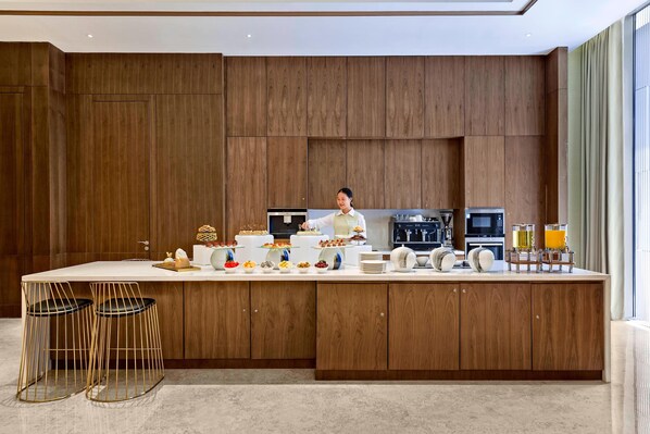 A modern kitchen with wooden cabinetry, a central island with stools, and various kitchen appliances. - Marriott Executive Apartments Hangzhou Yuhang (Hangzhou)