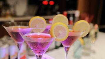 Tres vasos de martini con una bebida morada y rodajas de limón sobre una mesa.