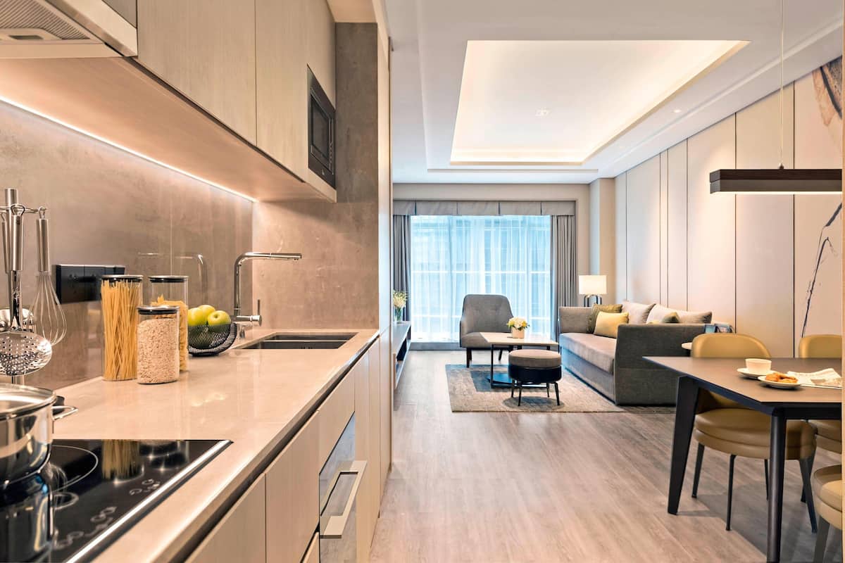 Een moderne keuken met een inbouwfornuis, een eethoek met een tafel en stoelen, en een woonkamer met een bank en salontafel.