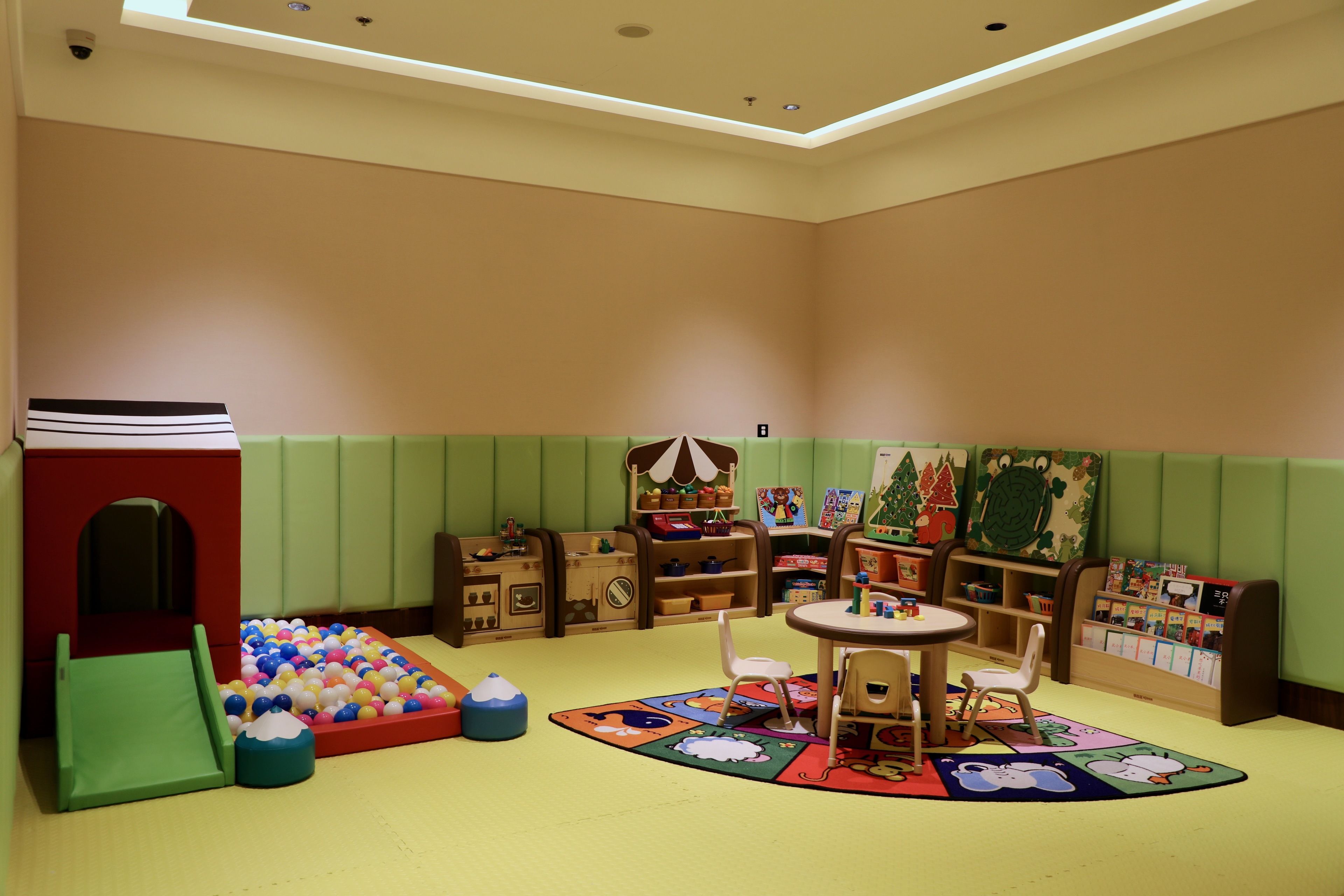 A children's playroom with a ball pit, a slide, and a table with chairs.
