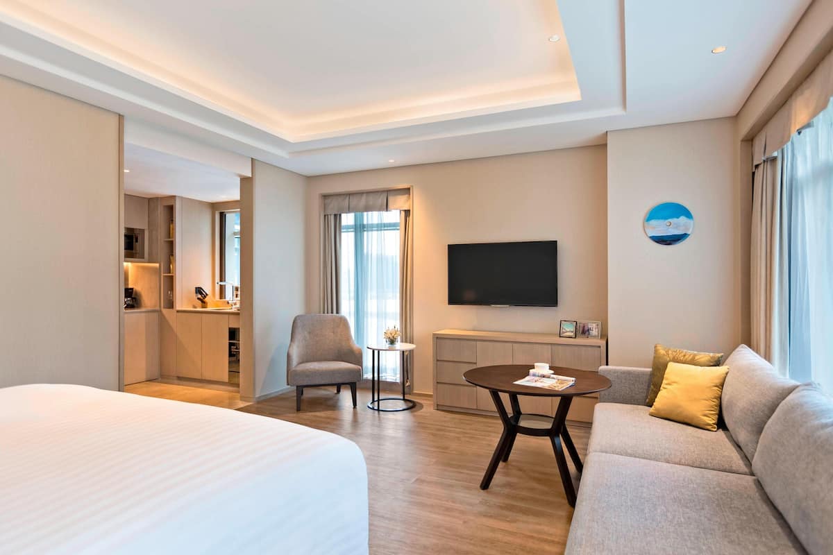 Een hotelkamer met een groot bed, een bank, een televisie en een tafeltje.