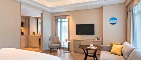 Une chambre d’hôtel avec un grand lit, un canapé, une télévision et une petite table.