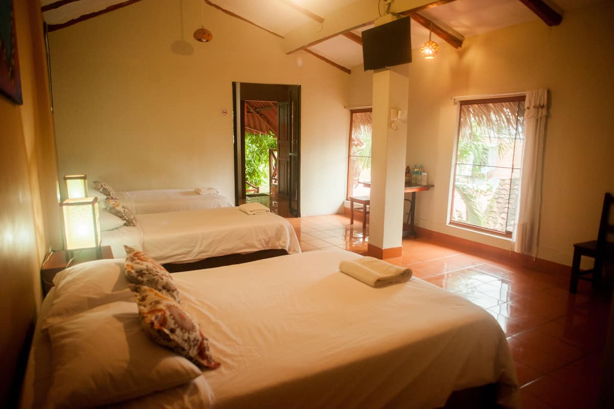 A hotel room with two beds, a small table, and a window with curtains.