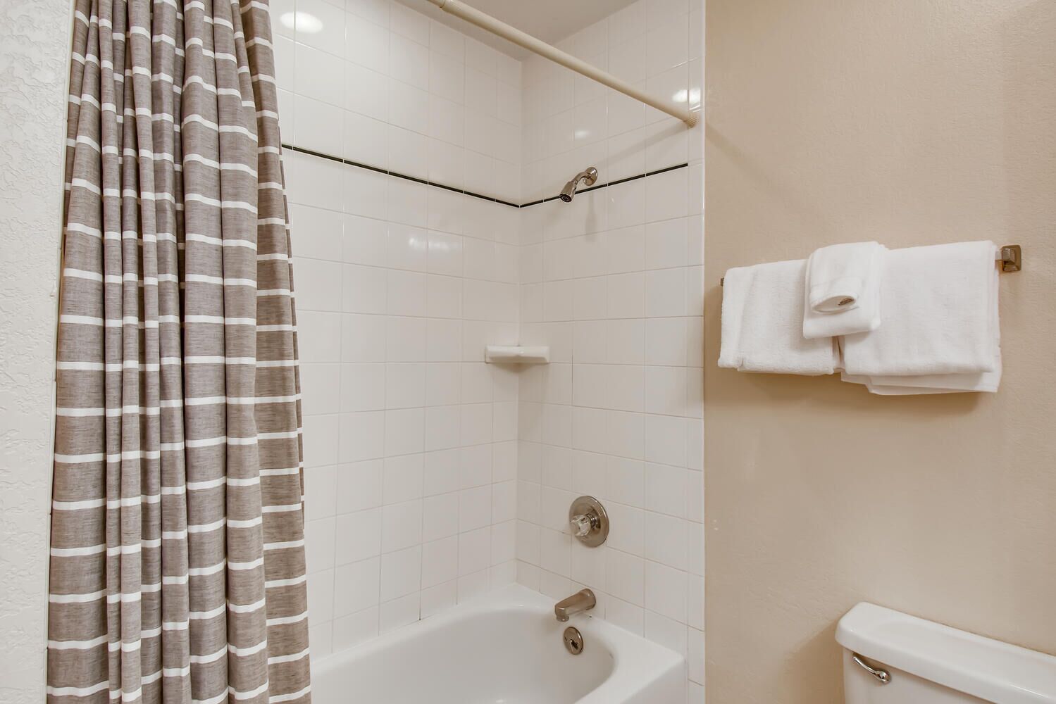 Une salle de bain équipée d’une douche, d’une baignoire et de toilettes. On y trouve un porte-serviettes avec deux serviettes.