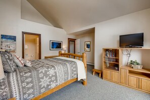 Une chambre à coucher avec un lit, une télévision, une bibliothèque et un petit bureau.