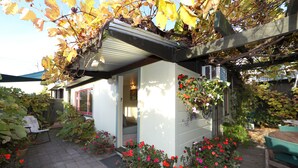 A small house with a covered patio, potted plants, and a wooden table.