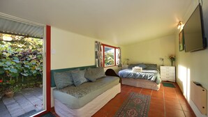 A bedroom with a bed, a sofa, a bedside table, and a window.