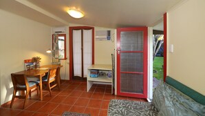 A compact living space with a dining area, a sofa, a small table, and a door leading to an outdoor area.