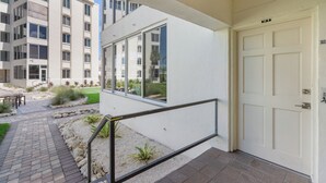 A modern apartment building with a white exterior, a visible door labeled "103," and a small outdoor area with a brick pathway and some landscaping. - Island House Beach Resort 10S (Siesta Key)