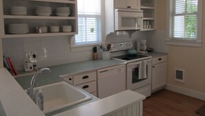 A kitchen with white cabinets, a microwave, a stove, and a sink. - Seabrook - On Turtle Time (Pacific Beach)