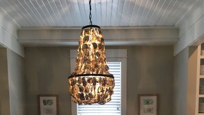 A dining area with a wooden table, four chairs, a unique chandelier, and two framed pictures on the wall. - Seabrook - On Turtle Time (Pacific Beach)