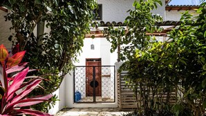 A stone staircase leading to a wooden door with a metal gate, surrounded by lush greenery and a clear blue sky. - Town House 9: Comfort and golf course view (Hacienda Iguana)