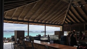 A bar area with a view of the sea, wooden furniture, and a bar counter. - Corner Villa with Stunning Sapphire Bay Views – Sleeps 6 w/Backup Generator. (St Thomas)